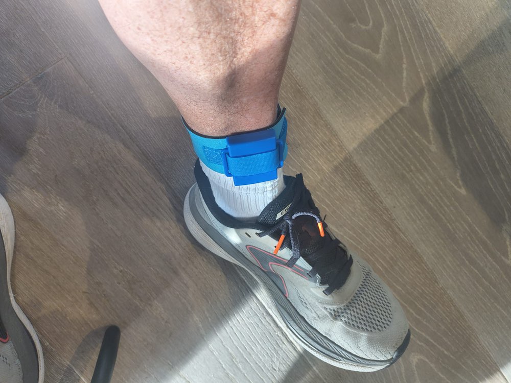 Timing chip on a blue strap worn around an ankle above a running shoe