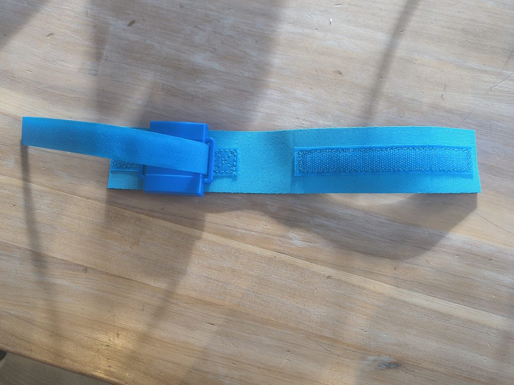 Timing chip threaded onto an open blue hook-and-loop strap laid flat on a table