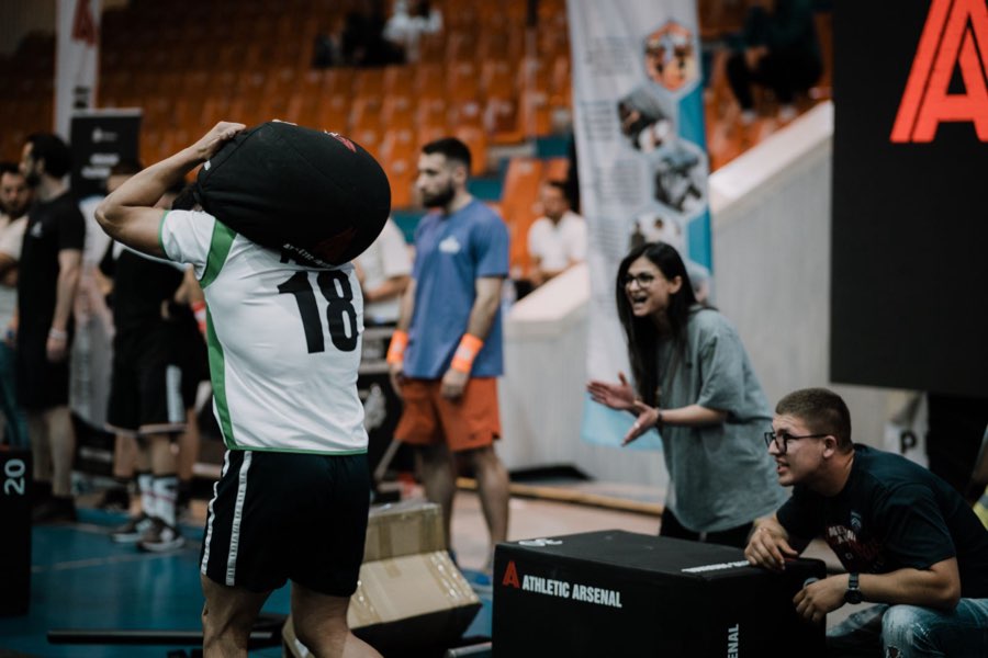 Athlete carrying a sandbag on their shoulder while spectators cheer them on