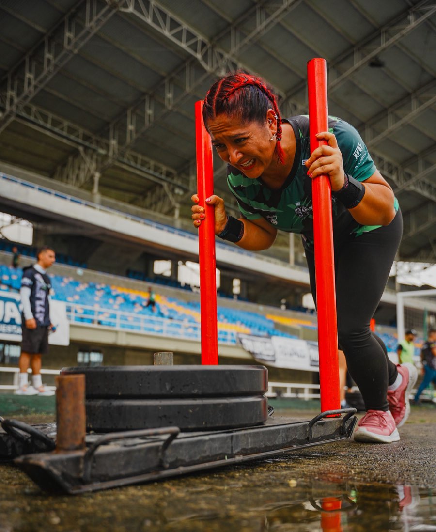 Athlete driving a weighted sled down a stadium track during a fitness competition